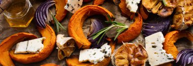 Fırınlanmış balkabağı, soğan, sarımsak, baharat ve Dorblu peyniri dilimleri parşömen kağıdında ve eski mavi taş arka planda. Üst görünüm.