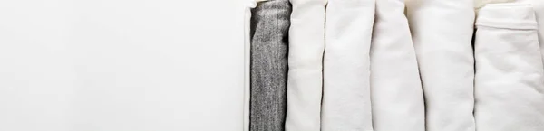 把白色和灰色的衣服整齐地折叠在一个容器里 放在衣柜里 或者在白色的背景上旅行 衣柜里的秩序 — 图库照片