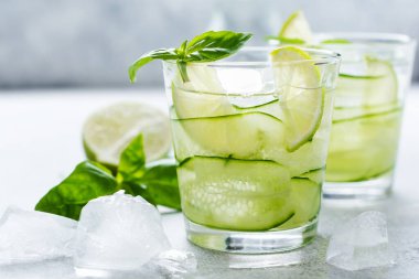 Limon, limon, salatalık ve buzlu fesleğenden yapılan ev yapımı limonata. Eski bir beton arka planda. Seçici odak.