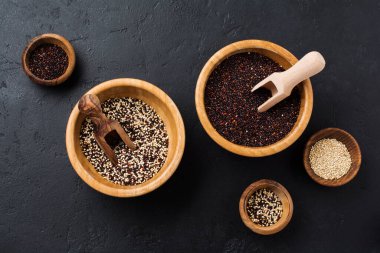 Beyaz, siyah ve karışık kinoa tanecikleri siyah taş bir arka planda bambu kabında tohumlar. Kopyalama alanı olan düz.