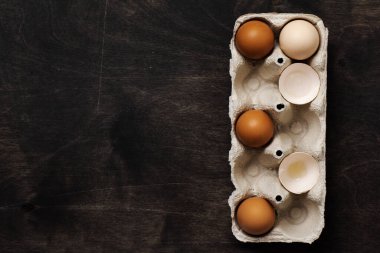 Beyaz ve sarı tavuk yumurtaları ve kabukları eski, siyah ahşap bir arka planda eski bir selüloz vintage konteynırda. Pişirme ve aşçılık geçmişi. Kopyalama alanı olan üst görünüm.