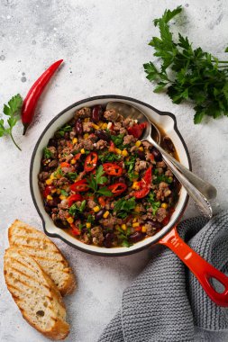 Geleneksel Meksika yemekleri - Domates soslu kıyma ve sebzeli Chili con carne hafif gri kayrak ya da beton arka planda dökme demir bir tavada. Kopyalama alanı olan üst görünüm.