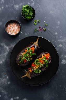 Farklı sebzeler, domates, biber, soğan ve maydanozla doldurulmuş patlıcan, siyah taş ya da beton masa arkaplanı. Üst görünüm.