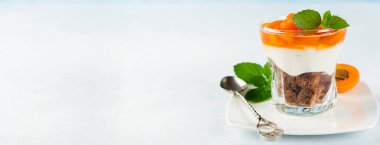 Çikolatalı bisküvi, vanilyalı krem peynir ve arka planda cam bir kasede kayısı reçeli. Seçici odak. 