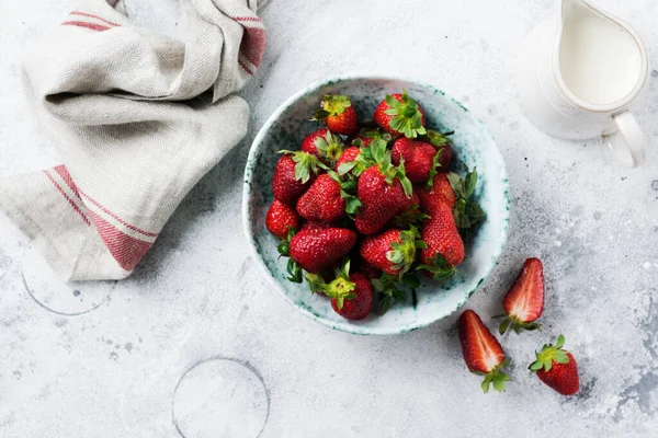 stock image Fresh strawberry in old ceramic bowl rustic with green leaves on gray concrete background. Healthy breakfast concept. Top view.