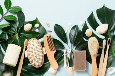 Çevre dostu banyo aksesuarları ya da mavi arka plandaki yapraklar üzerindeki spa aletleri. Kozmetik beton arka plan. Güzellik ve sıfır atık kavramı.