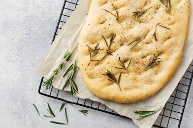 İtalyan geleneksel Focaccia ekmeği aromatik baharatlar ve açık gri arka planda biberiye. Üst görünüm.