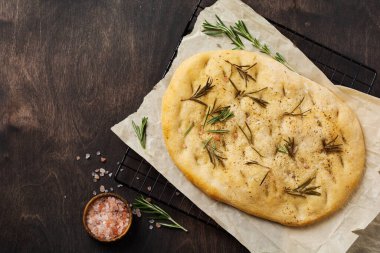 İtalyan geleneksel Focaccia ekmeği aromatik baharatlar ve eski ahşap masa arka planında biberiye. Üst görünüm.