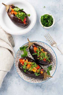 Farklı sebzeler, domates, biber, soğan ve maydanozla doldurulmuş patlıcan, gri taş ya da beton masa arkaplanı. Üst görünüm.