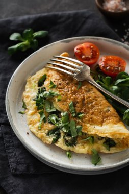 Doldurulmuş domatesli omlet, kırmızı dolma biber, krem peynir ve mısır veya koyu ahşap arka planda kuzu marulu fotokopi alanı. Kahvaltı için sağlıklı diyet yemeği. Seçici odak.