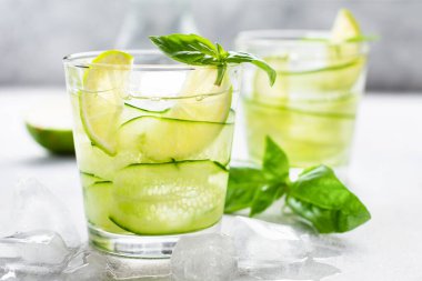 Limon, limon, salatalık ve buzlu fesleğenden yapılan ev yapımı limonata. Eski bir beton arka planda. Seçici odak.