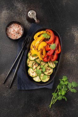 Izgara sebze parçaları kabak, kırmızı ve sarı biber tabakta kişniş buketi, mangal kömürünün üzerinde salata. Üst Manzara. Barbekü konsepti