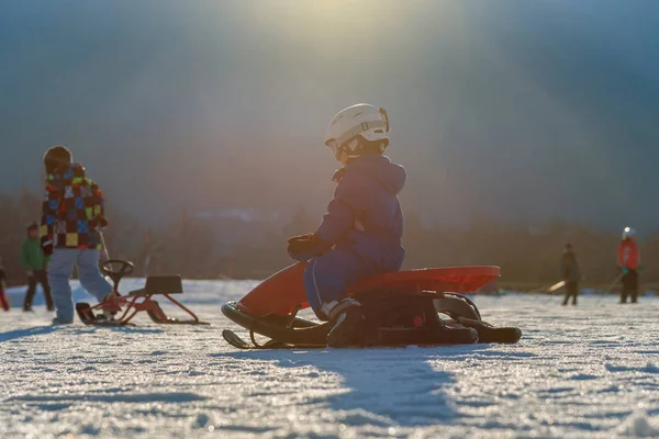 Child comes down from the mountain riding a red sled — Stock Photo, Image