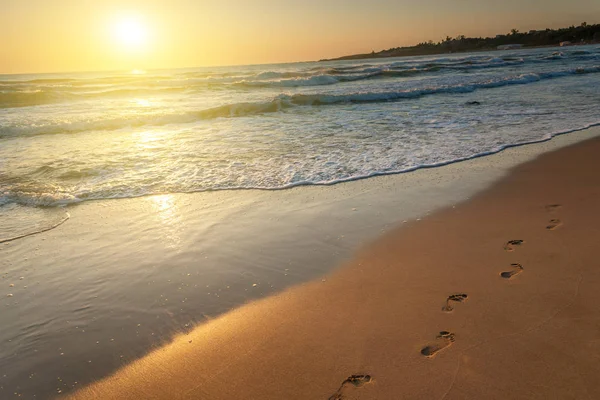 Plaża, fala i ślady na zachód słońca — Zdjęcie stockowe