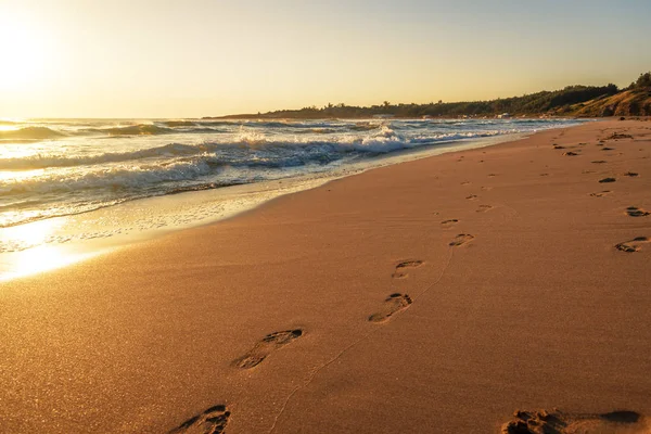 Gün batımında kumsal, dalga ve ayak izleri — Stok fotoğraf