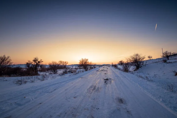 Téli naplemente táj fákkal és a mező út. — Stock Fotó