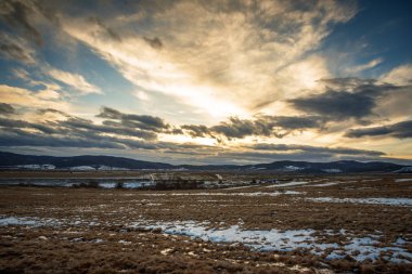 Gökyüzü ve bulutlar günbatımında bir çayırda.