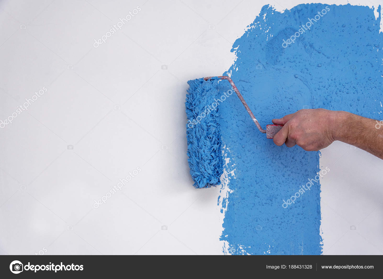 Male Hand Painting Wall In Blue With Paint Roller Stock Photo