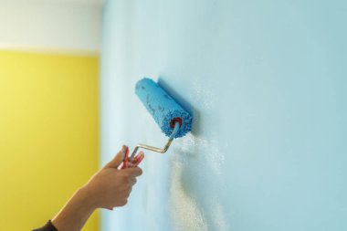 Dekoratörün el boyası silindirle duvarı.