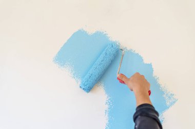 Dekoratörün el boyası silindirle duvarı.