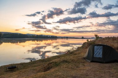 Sazan balığı ısırığı göstergeleri ve makaralı oltalar göl nehrinin yanındaki kapsüle yerleştirildi. Gün doğumunda balık tutmak.