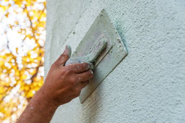 Ön cephe sıva uygulaması, işçilerin binanın dış cephesini alçılaması, yakın plan..