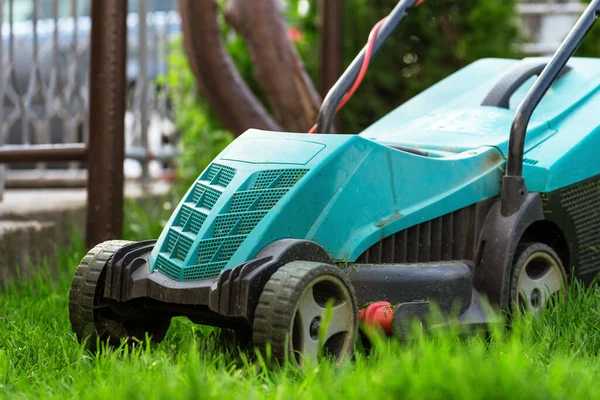 Gün batımında bahçede çim biçme makinesi.