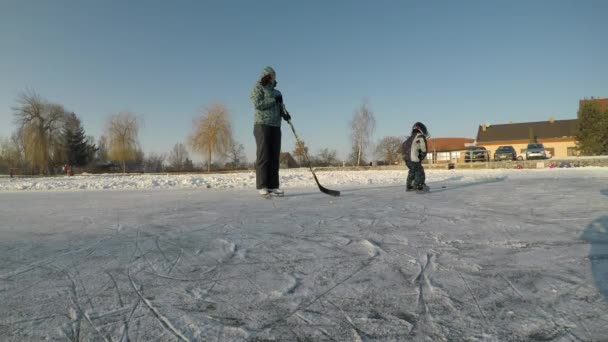 冬のスポーツの喜び 母と息子の凍った湖でホッケー — ストック動画