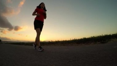 Gün batımında egzersiz. Genç kadın akşam Fitness run - ayak closeup. Ağır çekim. (Kasten düzensiz ufuk çizgisi - balık göz etkisi)