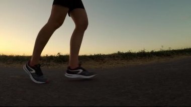 Gün batımında egzersiz. Genç kadın akşam Fitness run - ayak closeup. Ağır çekim. (Kasten düzensiz ufuk çizgisi - balık göz etkisi)