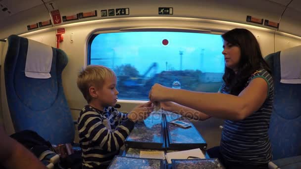 一个年轻的母亲和她的儿子乘火车旅行 妇女和儿童玩纸牌游戏 而在火车上旅行 — 图库视频影像