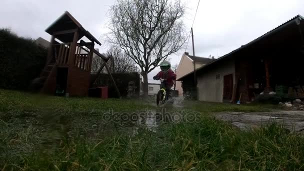 少年は 良い乗り心地を楽しんでいます 自転車で水たまりを運転します スローモーション — ストック動画
