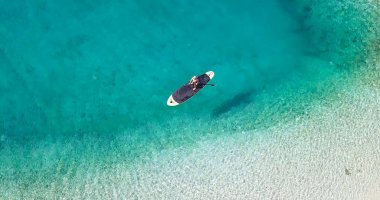 Deniz kenarında yaz zamanı. Kürek tahtasında çocuğun havadan görünüşü. Kes