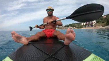 Genç adam bir kürek tahtasında. Hırvat kıyısındaki bir kürek tahtasında..