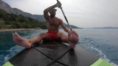 Genç adam bir kürek tahtasında. Hırvat kıyısındaki bir kürek tahtasında..