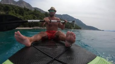 Genç adam bir kürek tahtasında. Hırvat kıyısındaki bir kürek tahtasında..