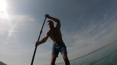 Delikanlı kürek çekiyor. Kürek çeken bir adamın alışılmadık bir görüntüsü. Kamera bir küreğe monte edildi.