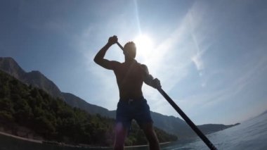 Delikanlı kürek çekiyor. Kürek çeken bir adamın alışılmadık bir görüntüsü. Kamera bir küreğe monte edildi.