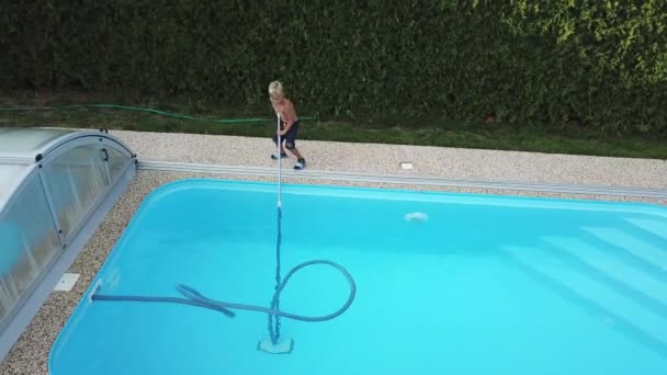 家庭用プールの掃除小さな男の子が吸い スイミングプールを掃除します 空中から見た季節の作品 — ストック動画