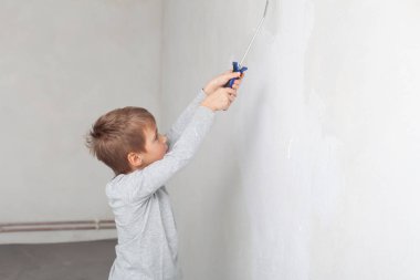 Odadaki duvarları boyarken küçük çocuk.