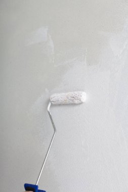 Odadaki duvarları boyarken küçük çocuk.