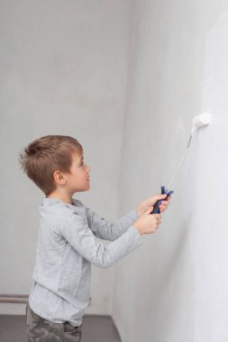 Odadaki duvarları boyarken küçük çocuk.