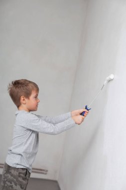 Odadaki duvarları boyarken küçük çocuk.