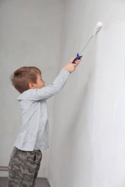 Odadaki duvarları boyarken küçük çocuk.