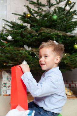 Çocuk Noel hediyelerini açarak seviniyor. Hıristiyan geleneği.