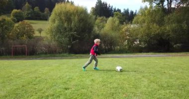 Küçük çocuklar futbol oynuyor. Çocuk kaleciye ateş eder ve kaleye sevinir..