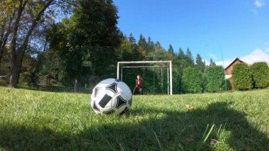 Küçük çocuklar futbol oynuyor. Çocuk kaleciye ateş eder ve kaleye sevinir..