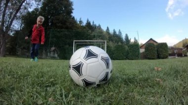 Küçük çocuklar futbol oynuyor. Çocuk kaleciye ateş eder ve kaleye sevinir. Oğlan topla kaleye koşuyor..