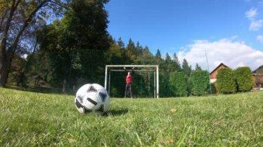 Küçük çocuklar futbol oynuyor. Çocuk kaleciye ateş eder ve kaleye sevinir..