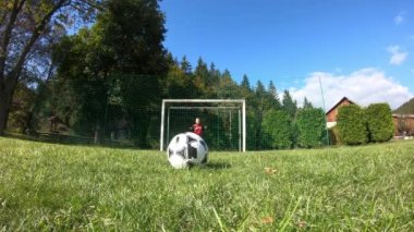 Küçük çocuklar futbol oynuyor. Çocuk kaleciye ateş eder ve kaleye sevinir..